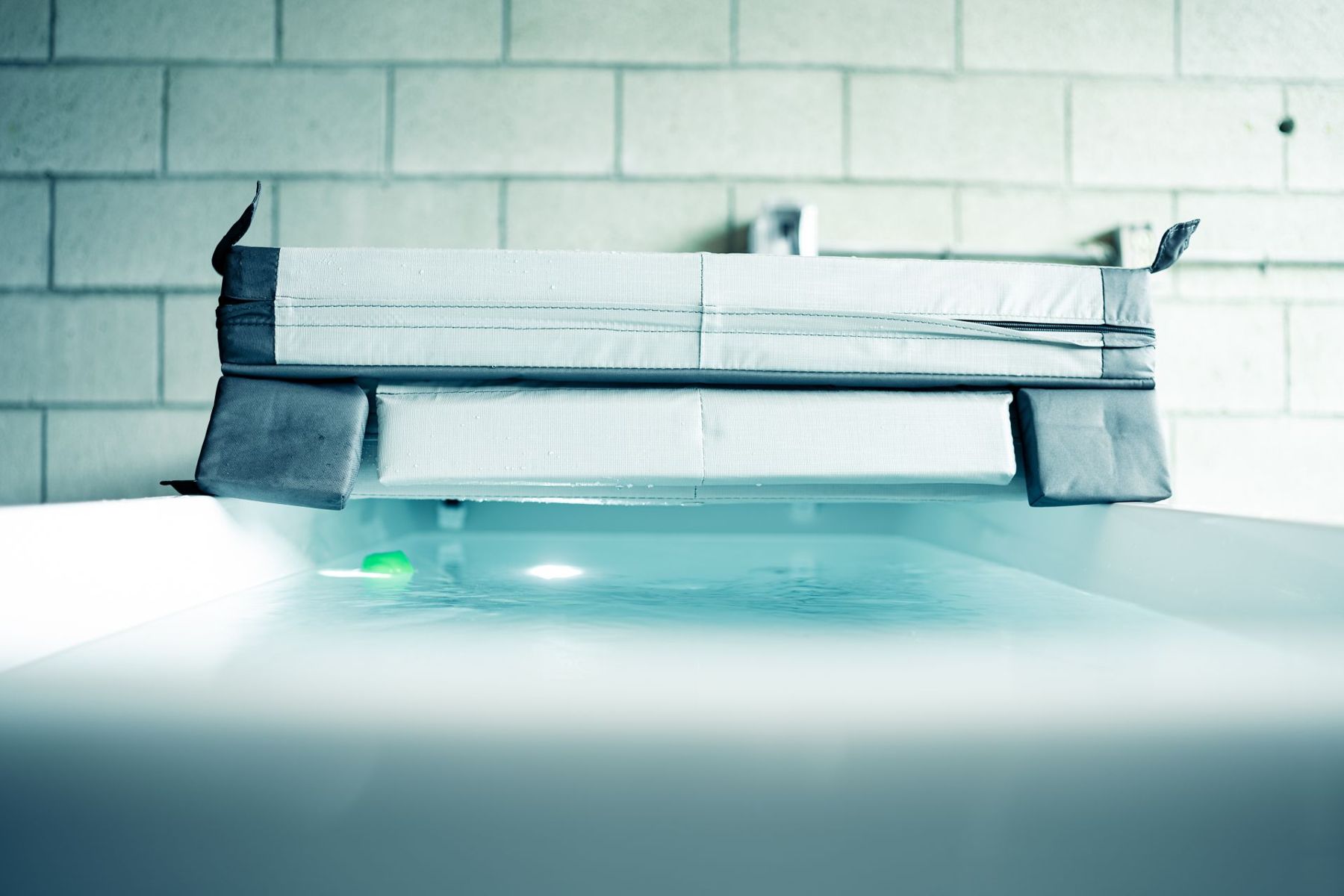 A cold plunge tub with a cover in a tiled room